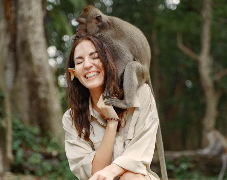 Woman laughs at a monkey on her shoulder in a zoo trial