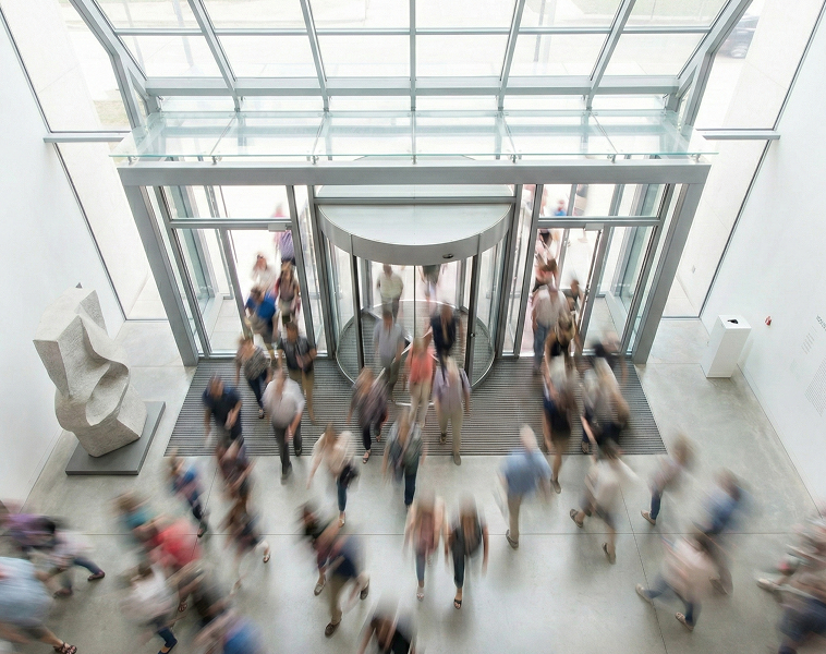 A stream of visitors entering and leaving a modern museum front entrance